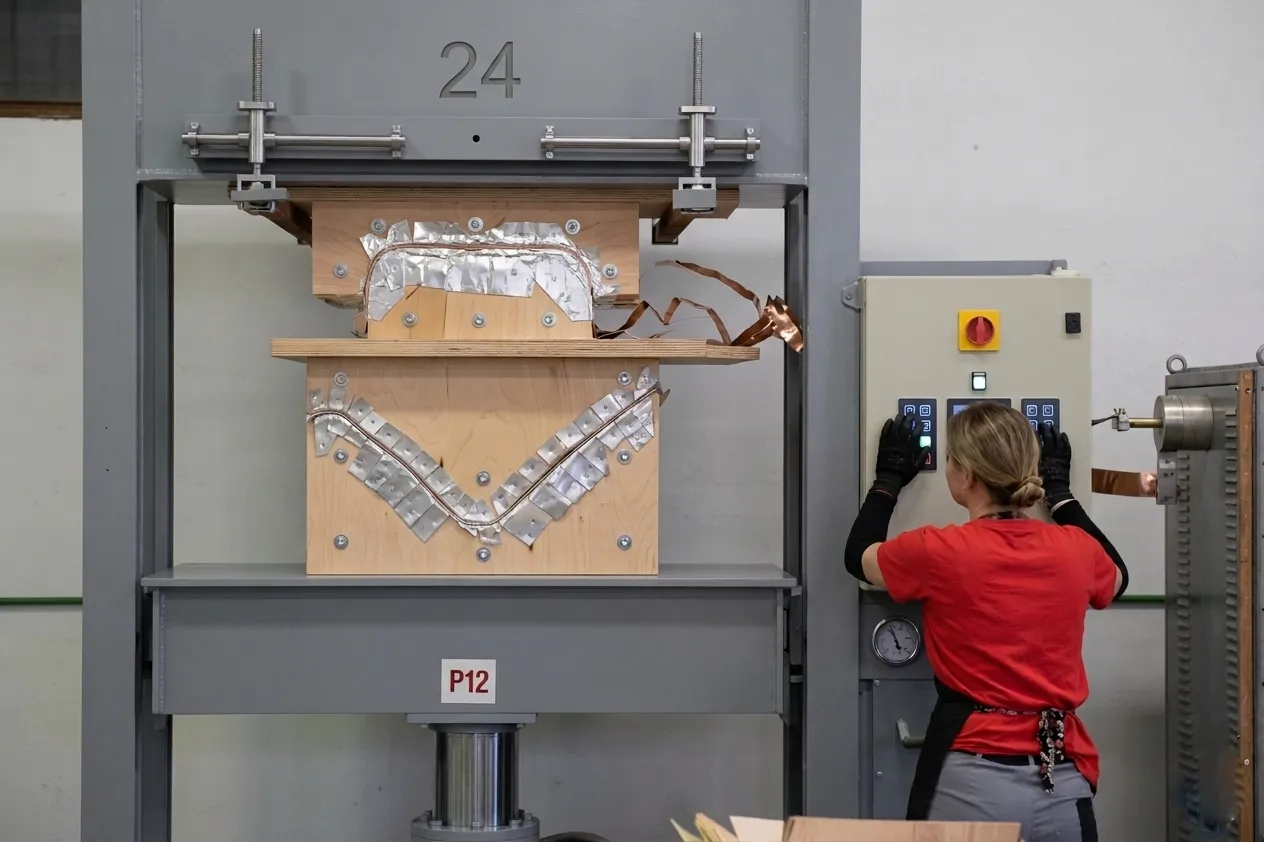 A hydraulic press forming a curved plywood backrest in the Breza plant.