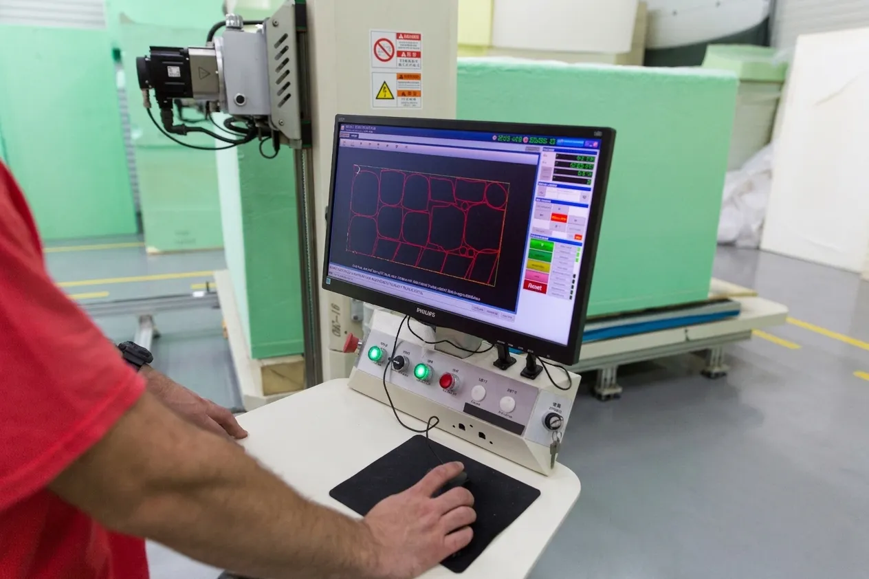 An operator monitoring a CNC nesting layout on the control screen.