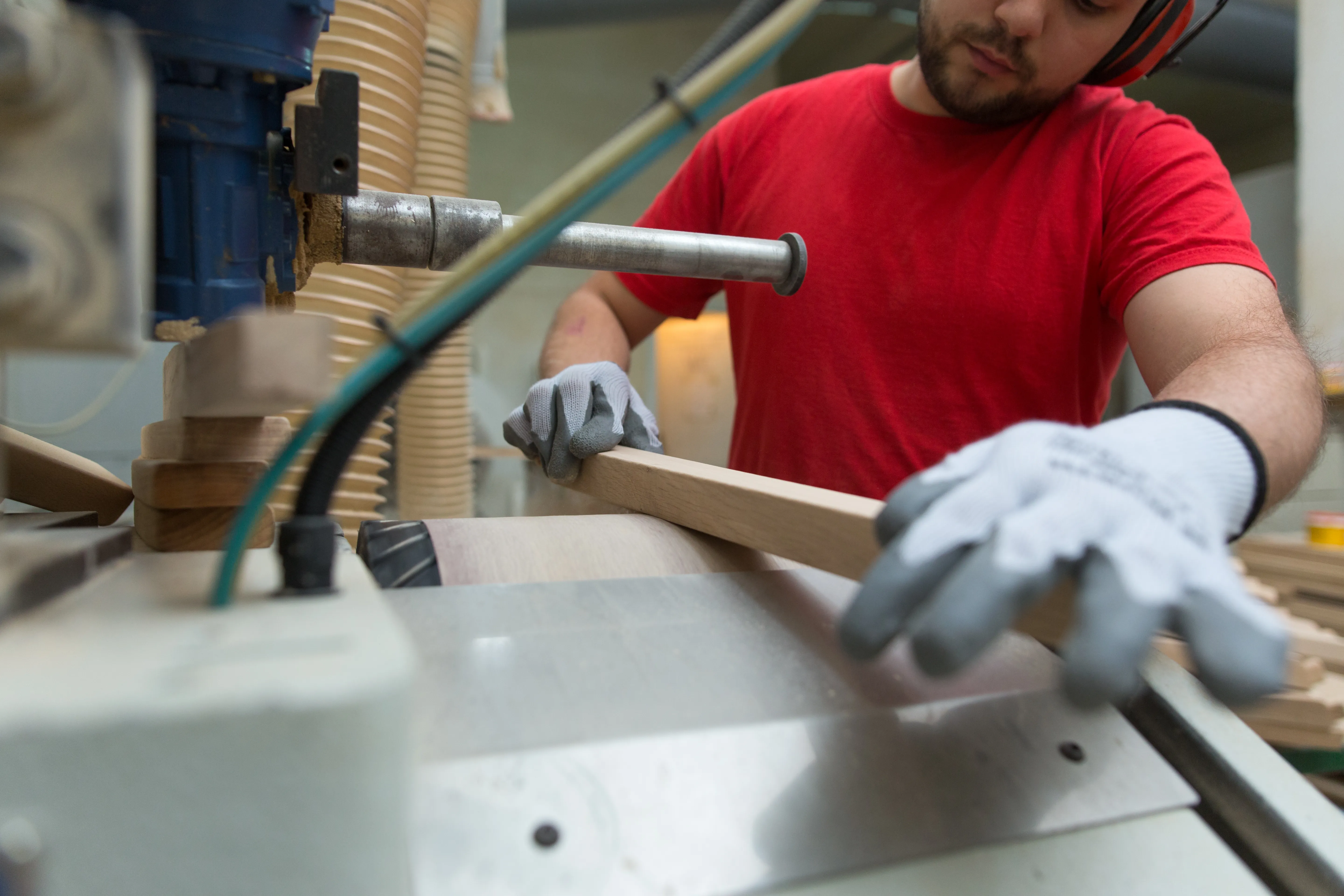 A worker shaping a curved chair component at a router.