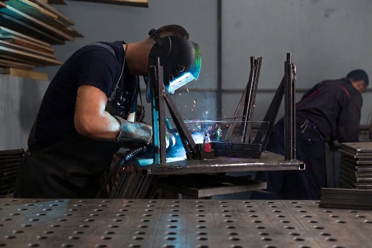 A welder joining a metal chair frame in the Visoko metal shop.