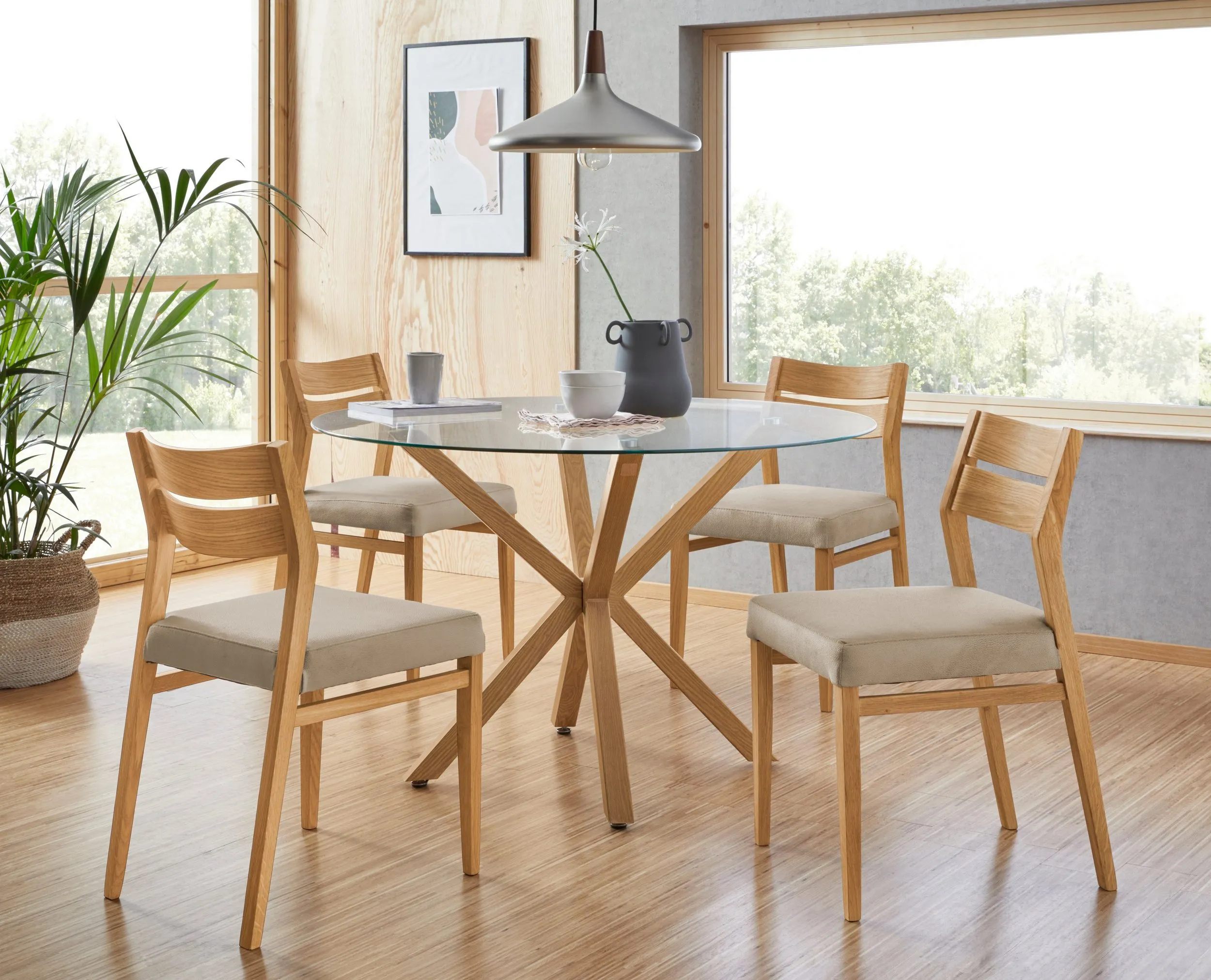 Solid oak chairs around a round glass-top dining table.