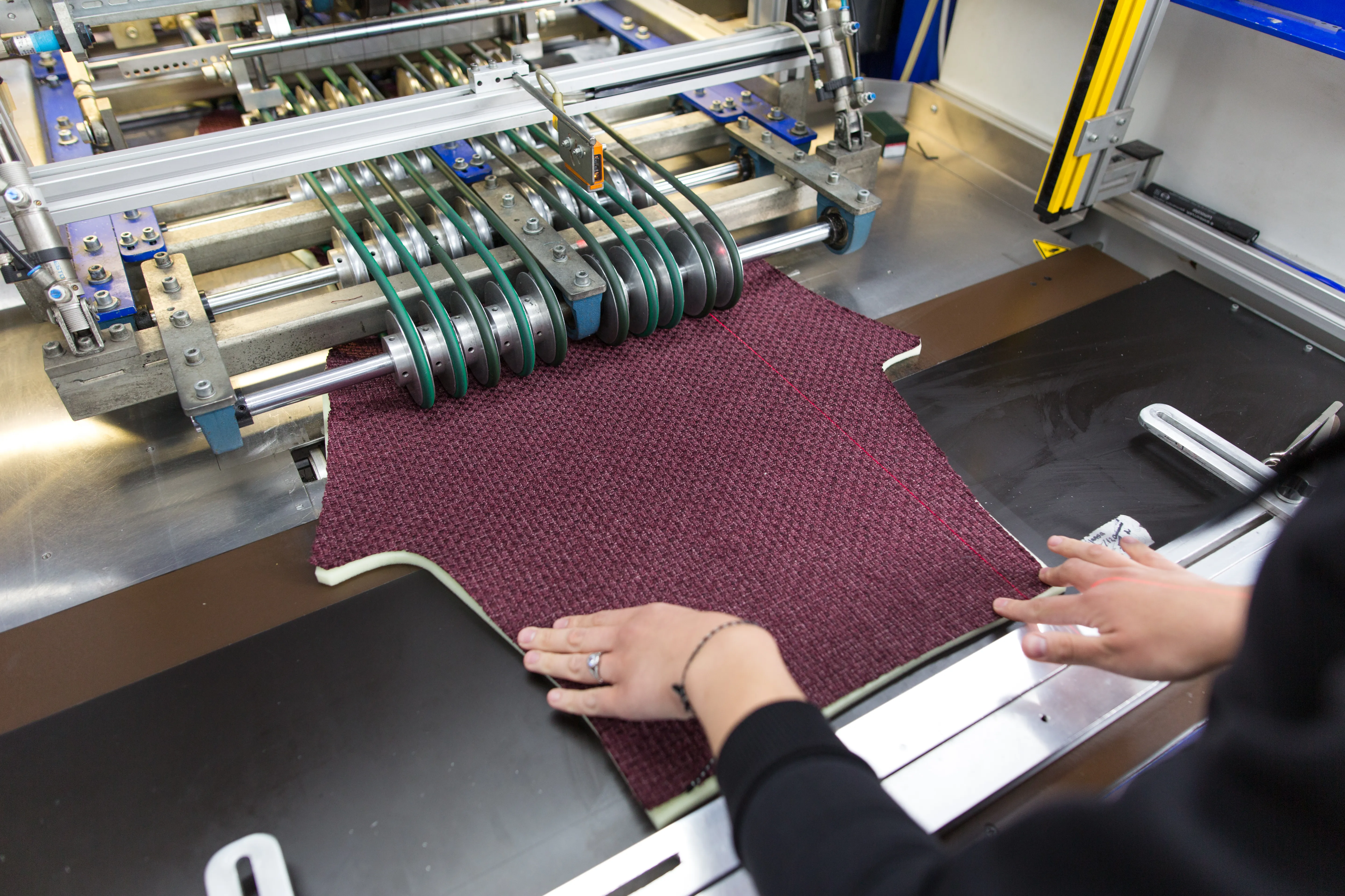 A heat-press station laminating a fabric seat panel.